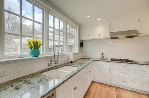 This gorgeous kitchen offers a front-row seat to nature, with elegant finishes and a calming, scenic backdrop