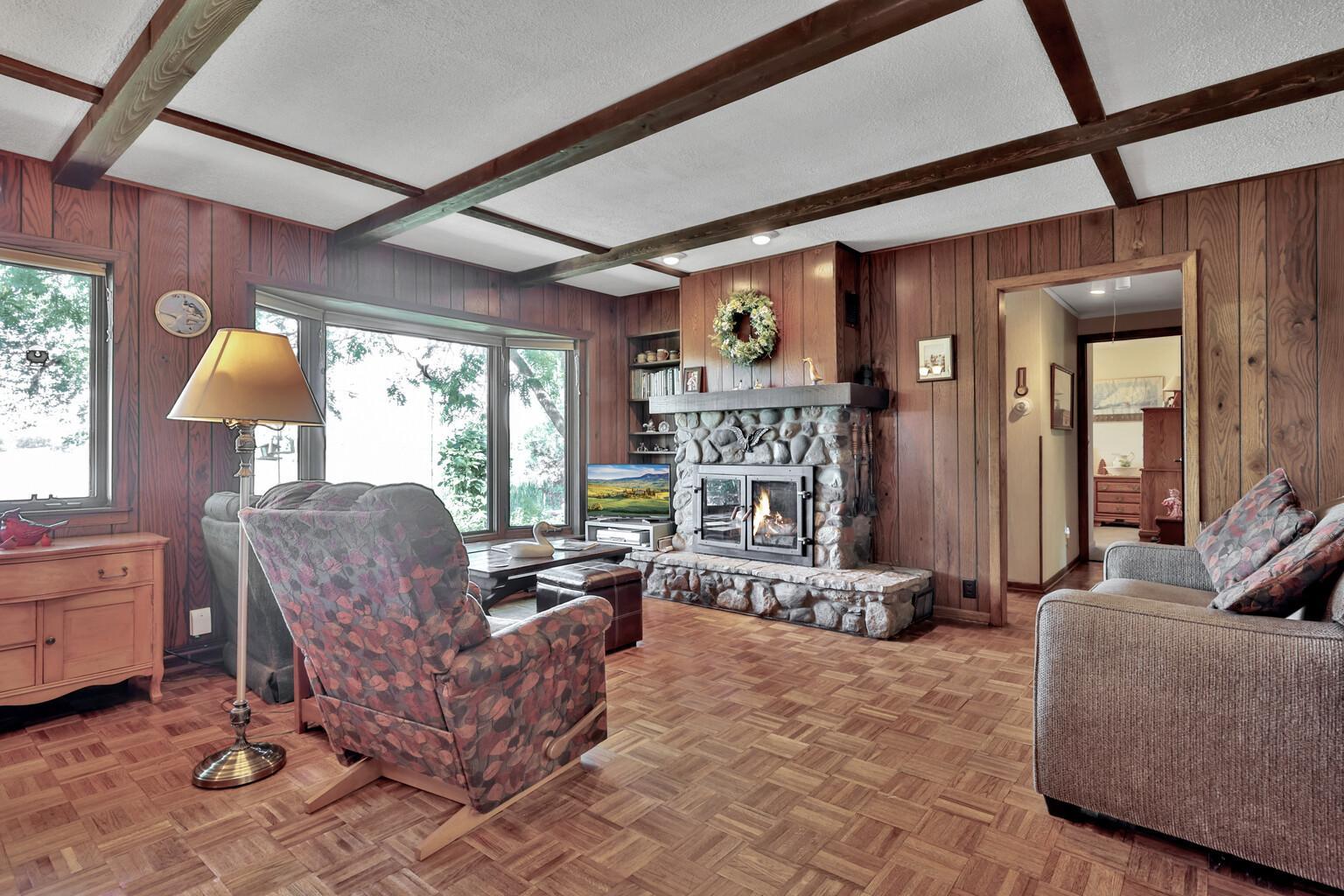 Spacious lakeside living room with cozy wood burning fireplace with stone surround.