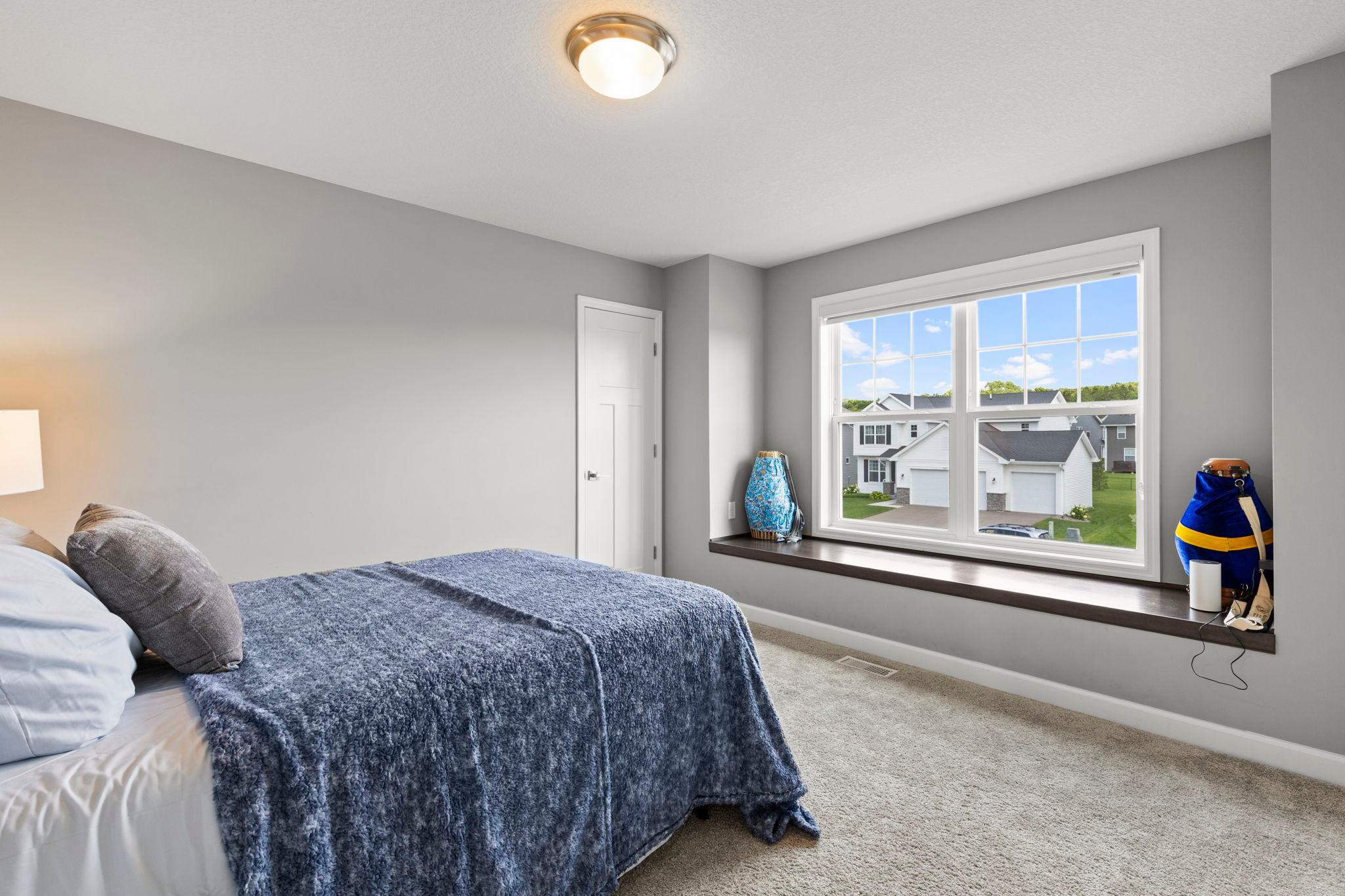 A look at bedroom three with a walk-in closet and a front-facing window with a bench ledge.