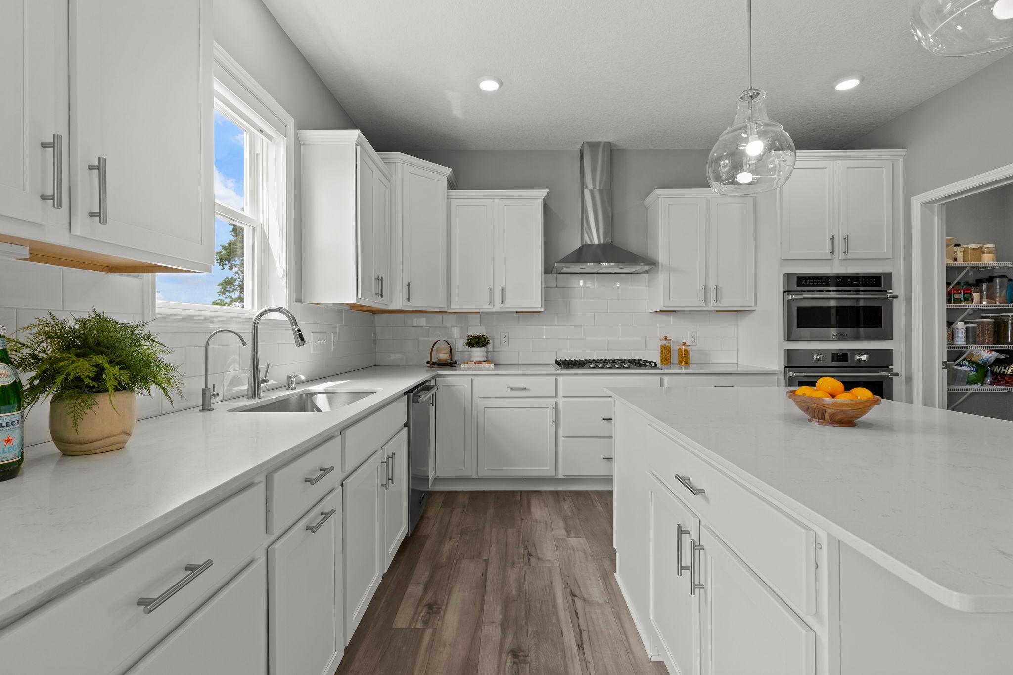 Stainless steel appliances including a gas cooktop with vent hood complement the spacious 5’ x 4’ walk-in pantry and thoughtfully designed layout.