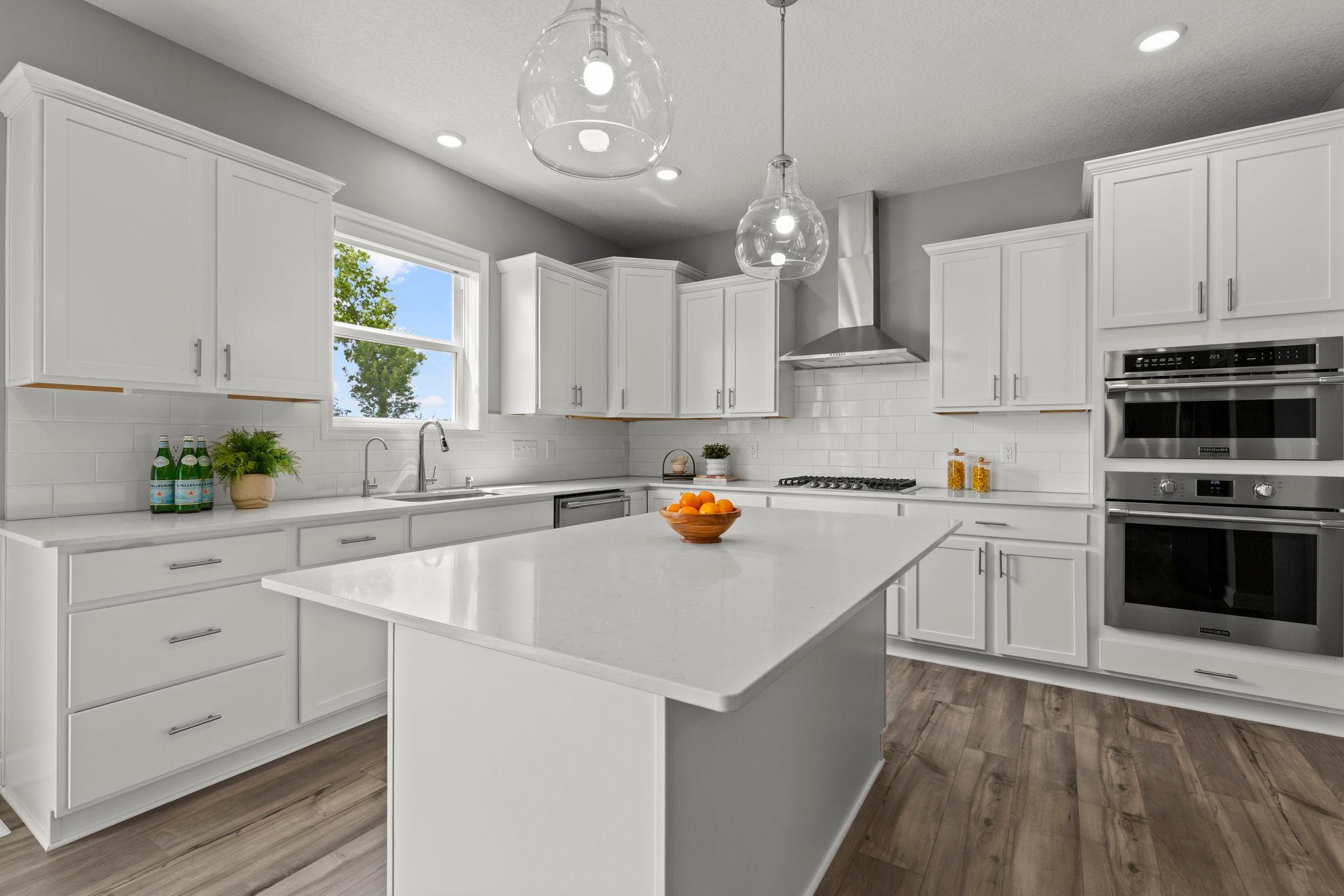 The chef-inspired kitchen is the heart of the home, featuring expansive quartz countertops, a large center island with breakfast bar seating, and abundant crisp white cabinetry.