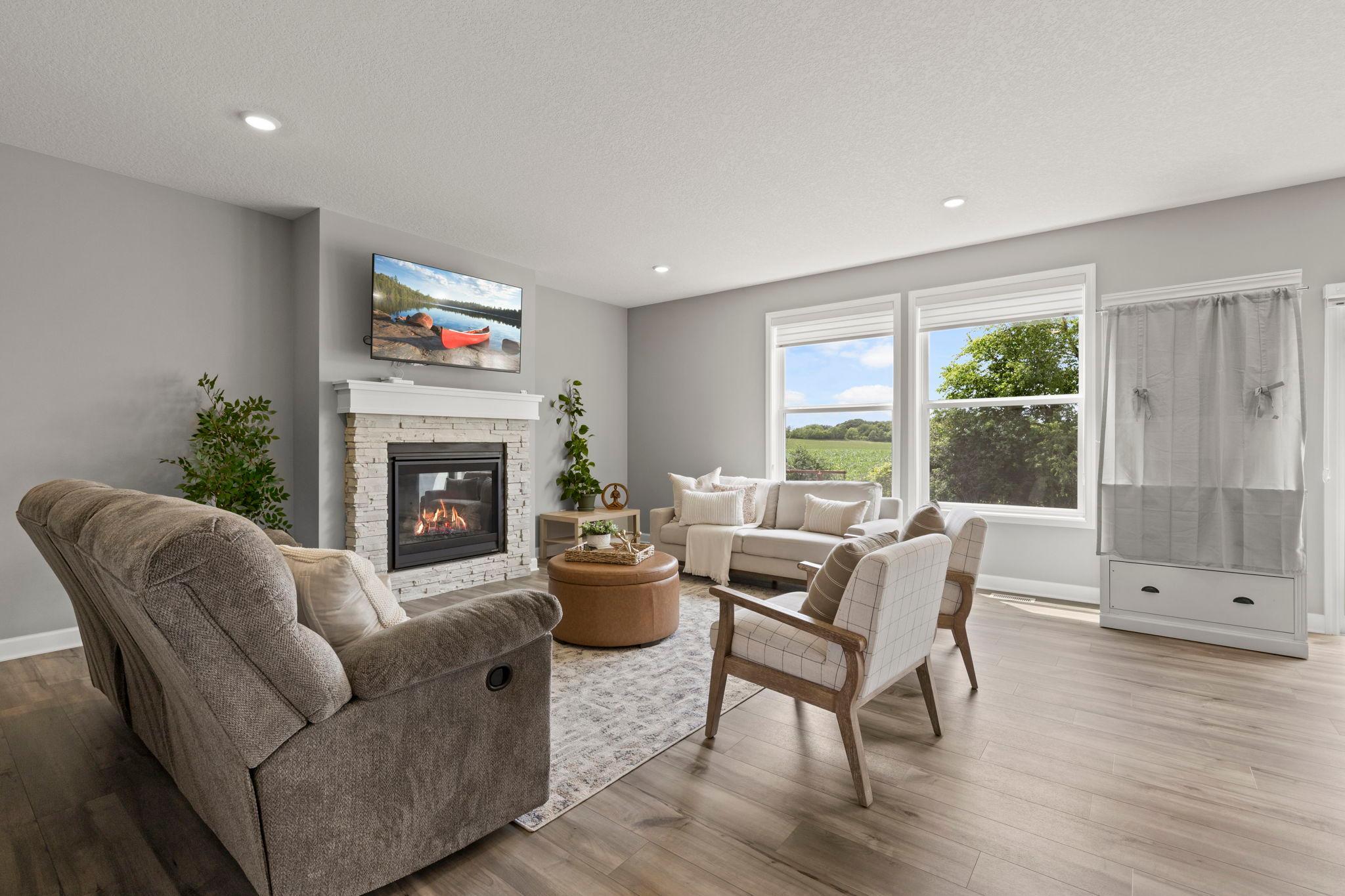 The adjacent living room offers a warm and welcoming atmosphere with a gas fireplace accented by a beautiful mantel and oversized windows that fill the space with natural light.