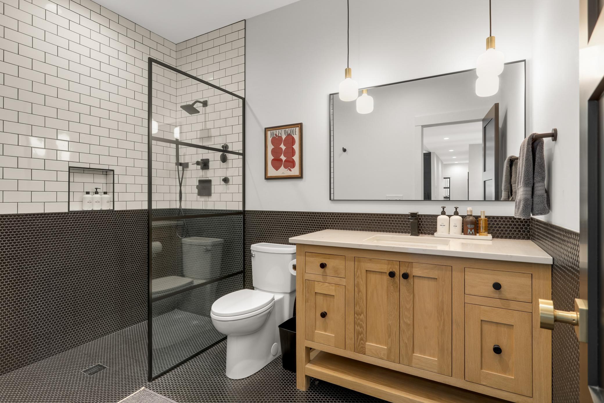 Hall bath with custom steel & glass shower door, penny tile on heated floor & wall finished with classic white subway tile & dark grout. Custom white oak vanity with Danbury marble counter