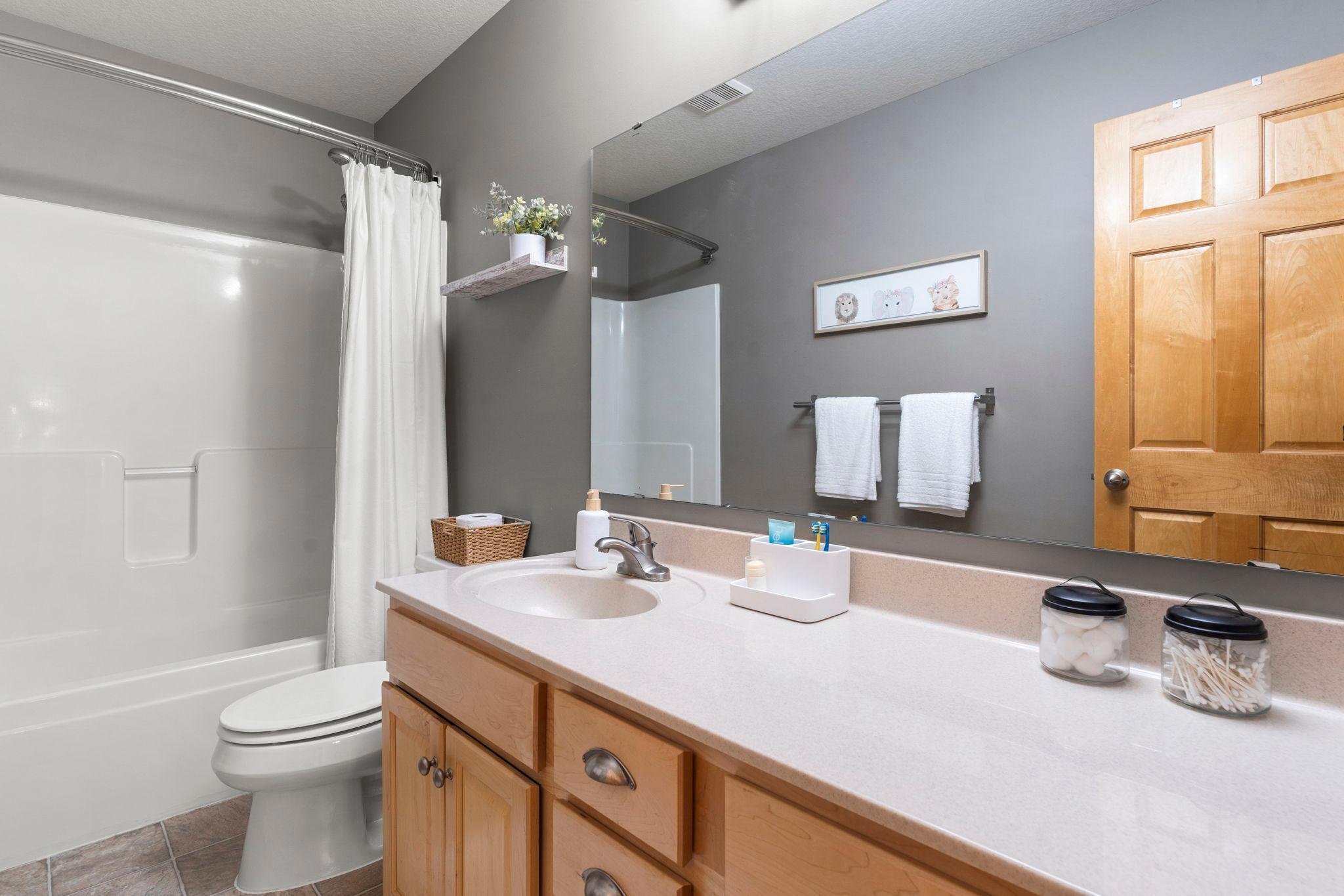 The upper-level shared full bathroom with a large single vanity and tub and shower combination.