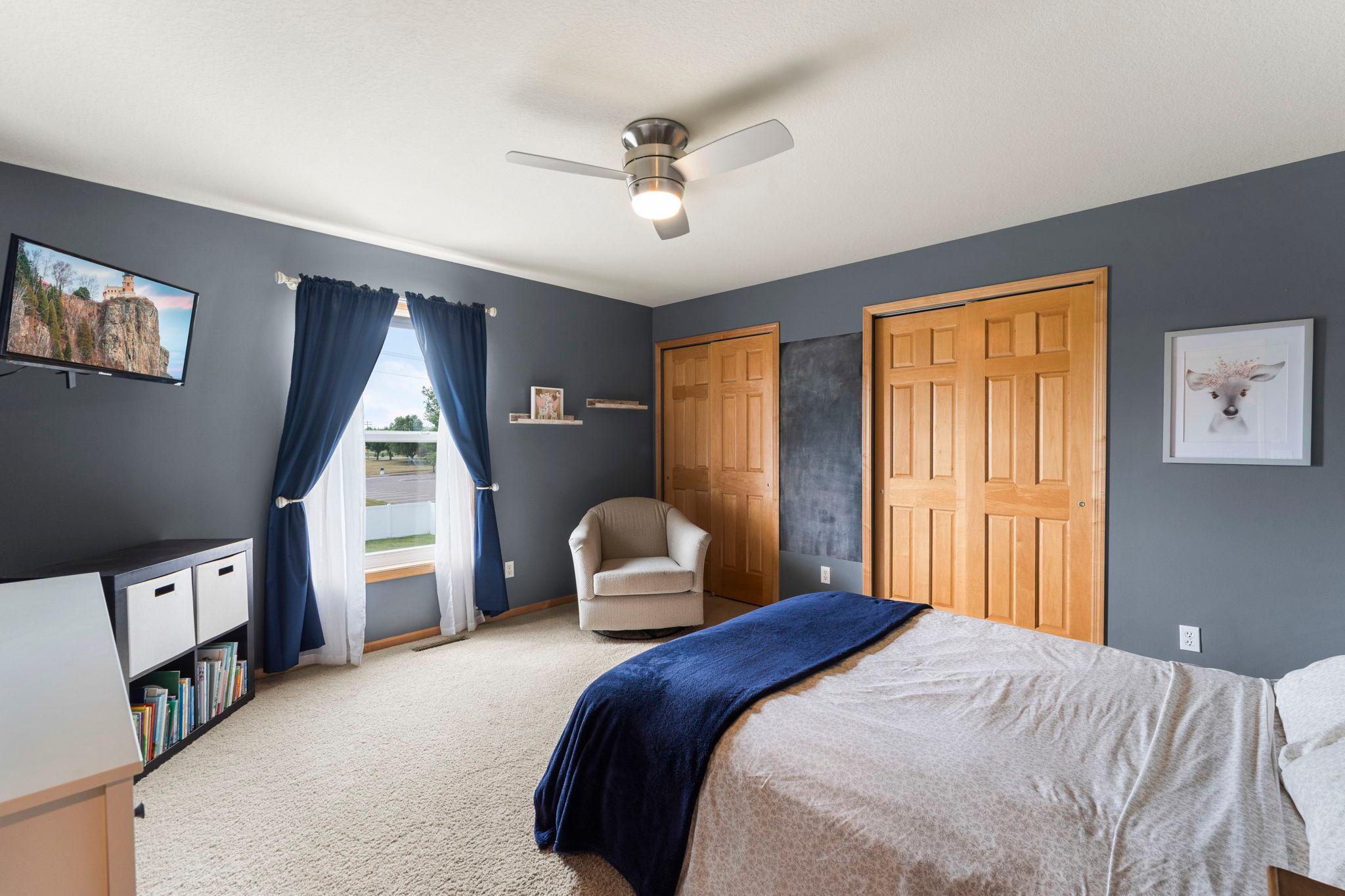 Bedroom two on the upper level featuring dual closets, carpeting, and a ceiling fan.