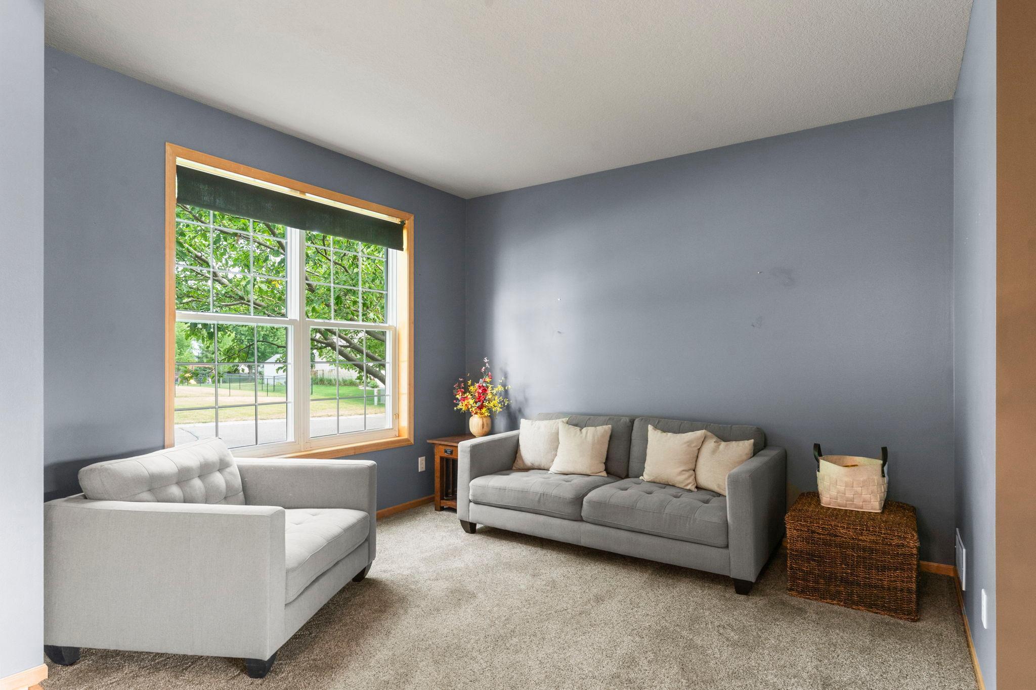 Near the foyer, a comfortable sitting area with carpeting and a large front-facing window provides peaceful neighborhood views.