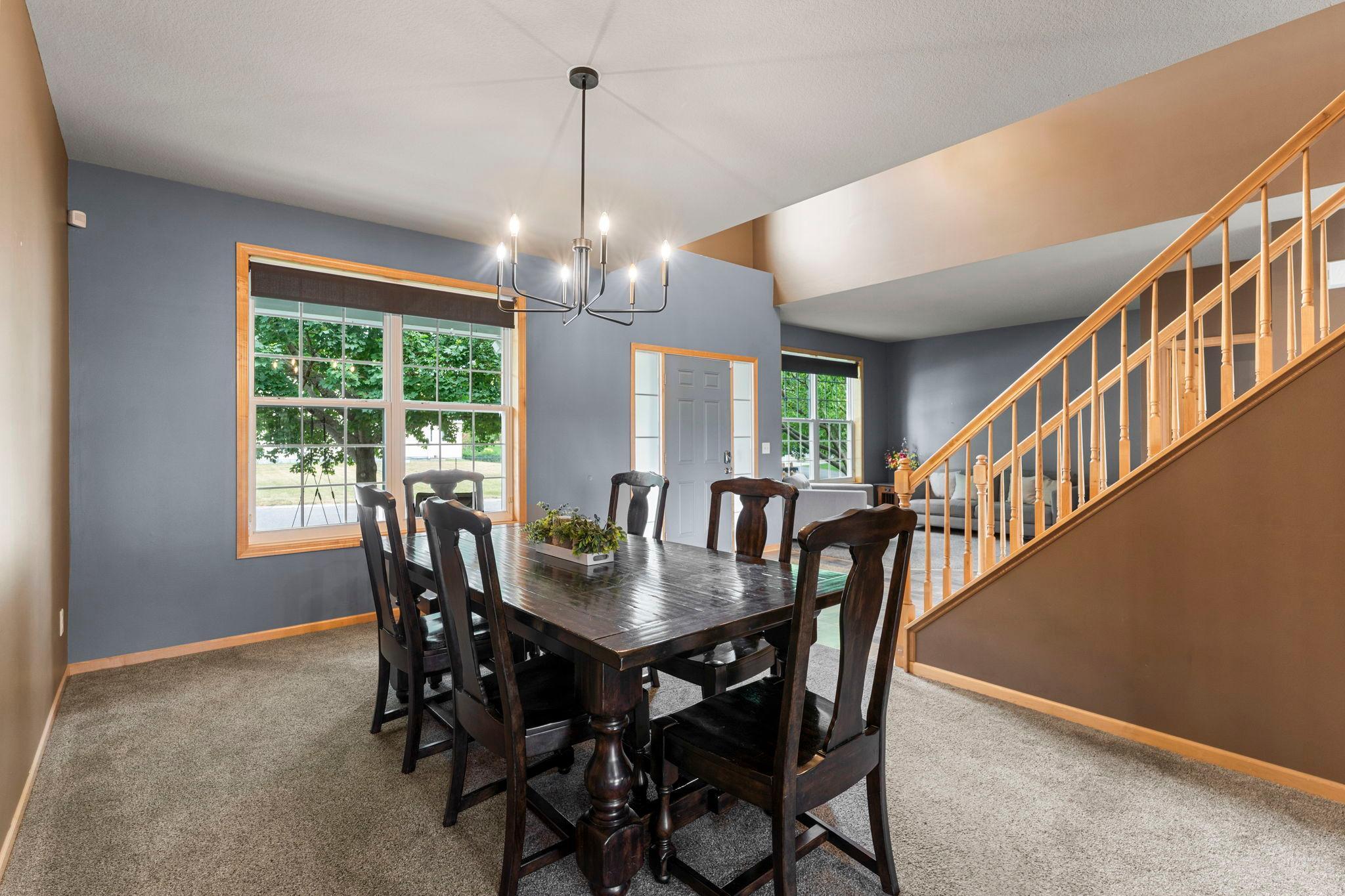 The main level also includes a formal dining room with a modern chandelier and front-facing window, ideal for hosting meals and celebrations.