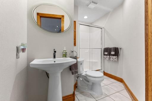 Lower level bathroom features a pedestal sink, tiled flooring and walk-in shower.