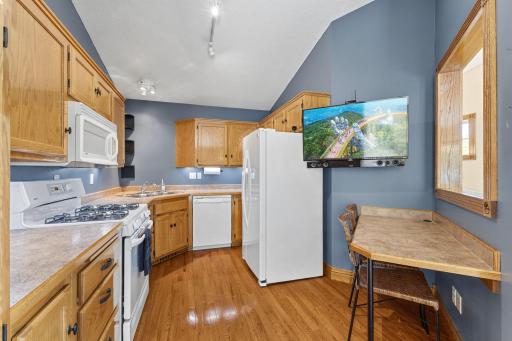 Functional kitchen with warm wood cabinetry, hardwood flooring and a convenient breakfast bar.