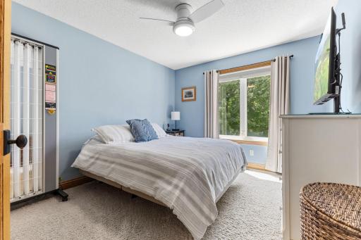 Bright bedroom with carpeting, a large window, and a ceiling fan.