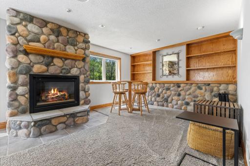 The lower level is complete with a striking stone fireplace and built-in shelving.