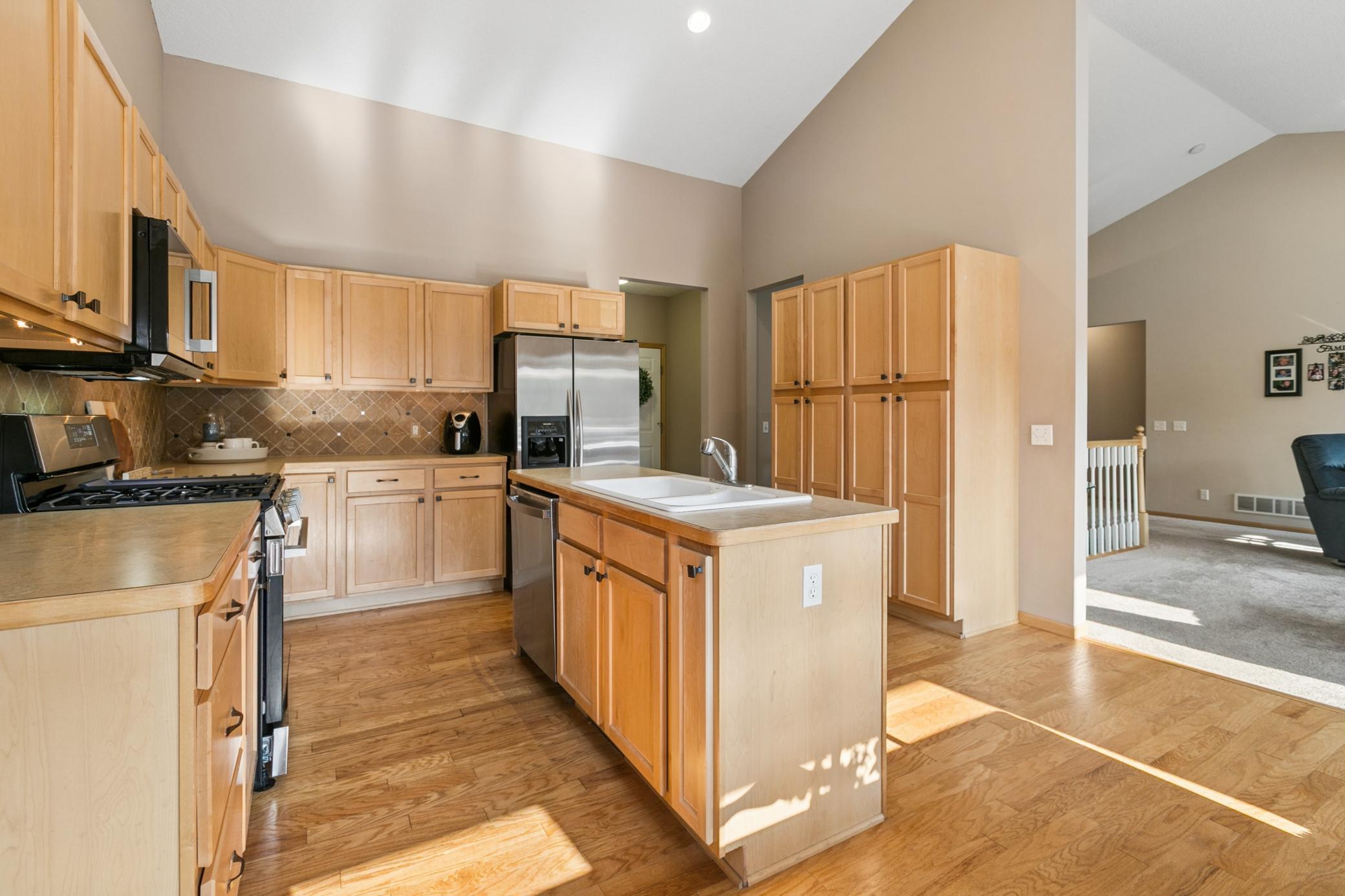 Kitchen/main floor highlights include vaulted ceiling, stone backsplash, open floor plan and access to outdoor space to enjoy meals on the deck.