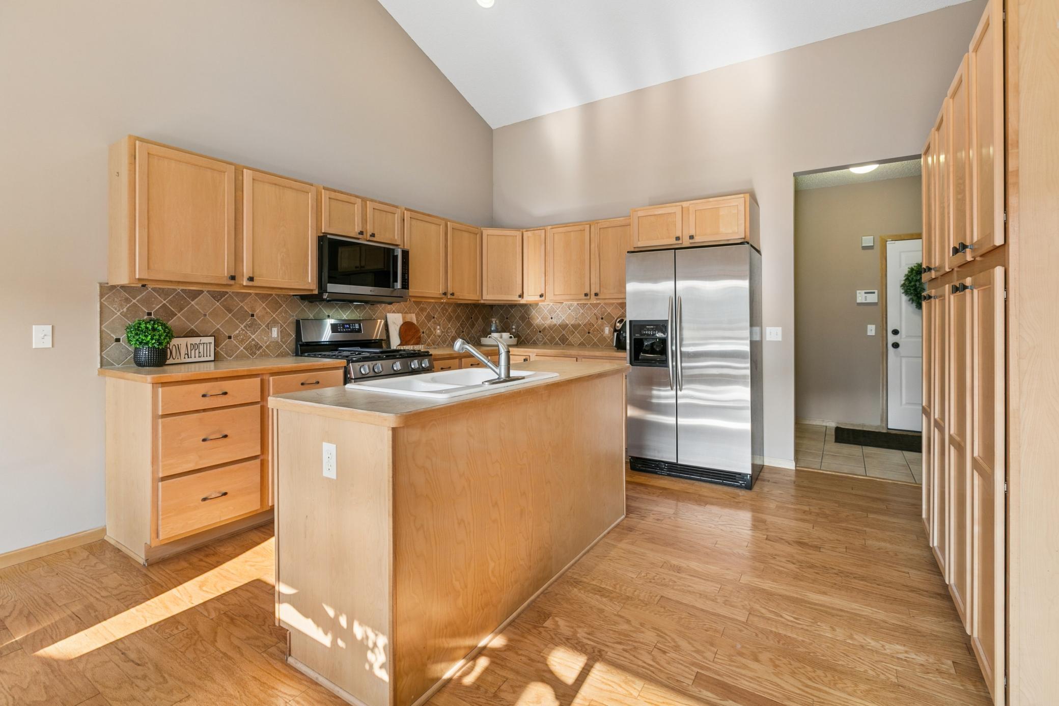 Natural, gleaming hardwood floors, light maple cabinetry, upgraded stainless appliances and ample storage throughout this kitchen.