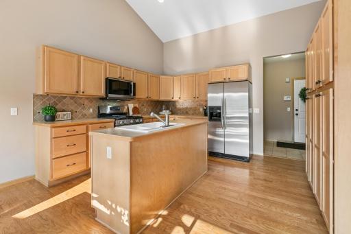 Natural, gleaming hardwood floors, light maple cabinetry, upgraded stainless appliances and ample storage throughout this kitchen.