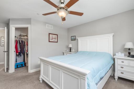 Spacious primary bedroom with walk-in closet, ceiling fan and large windows with room darkening blinds.