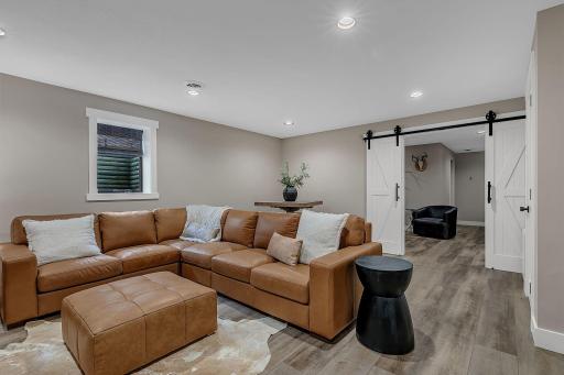 Another view of the lower-level living room, featuring beautiful decorative barn doors that can separate the living space from the dedicated office area.