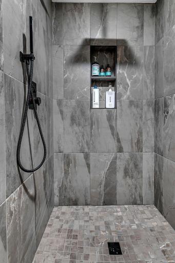 A look at the large tiled walk-in shower in the lower-level bathroom, featuring a clean, modern design and plenty of room to relax.