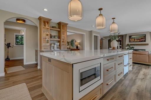 The island provides ample storage, a seamlessly integrated microwave, and an additional refrigerator dedicated to keeping fresh produce and vegetables conveniently accessible.