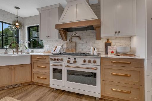 A stunning chefâs kitchen with a statement range, custom wood-and-white cabinetry, beautiful brick backsplash, and convenient pot filler. Every detail combines style and functionality in this exceptional cooking space.