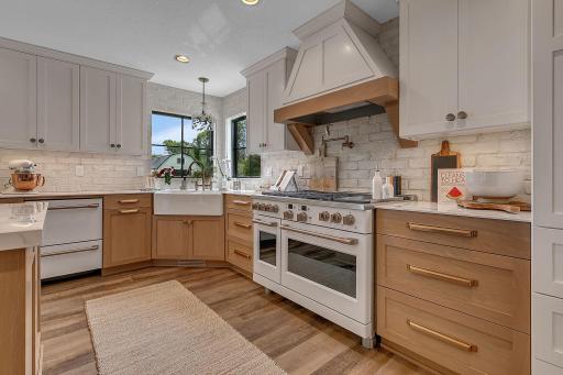 A beautifully designed gourmet kitchen featuring custom cabinetry, a striking range hood, farmhouse sink, and premium appliances, creating a stylish and highly functional space for cooking and gathering.