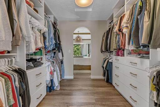 A spacious walk-through custom closet offers exceptional organization with abundant hanging space, built-in drawers, and thoughtful storage throughout.