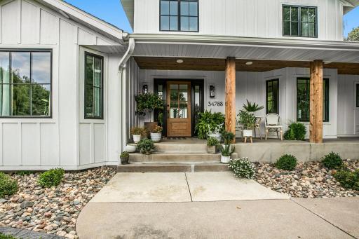 A beautiful front porch with wood beams, inviting seating, and thoughtfully designed landscaping creates the perfect spot to sit back, relax, and enjoy the outdoors.
