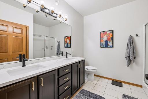 Double vanity in the primary bath with large walk-in shower and full-sized stackable washer and dryer.