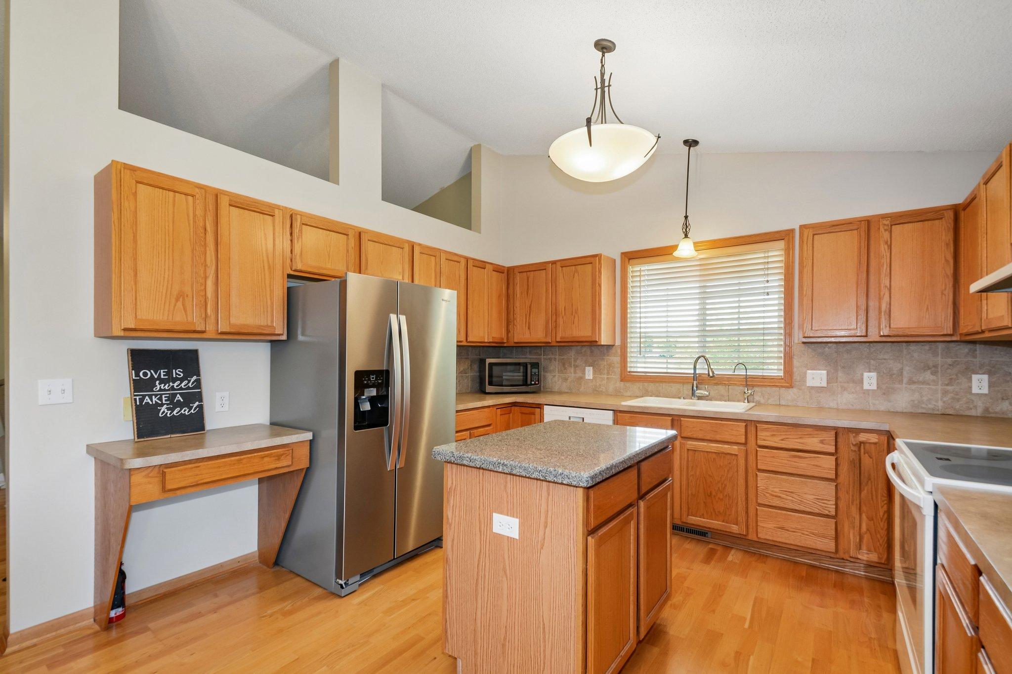 The kitchen offers plenty of counter space, and abundance of cabinetry, a new refrigerator and a center island.