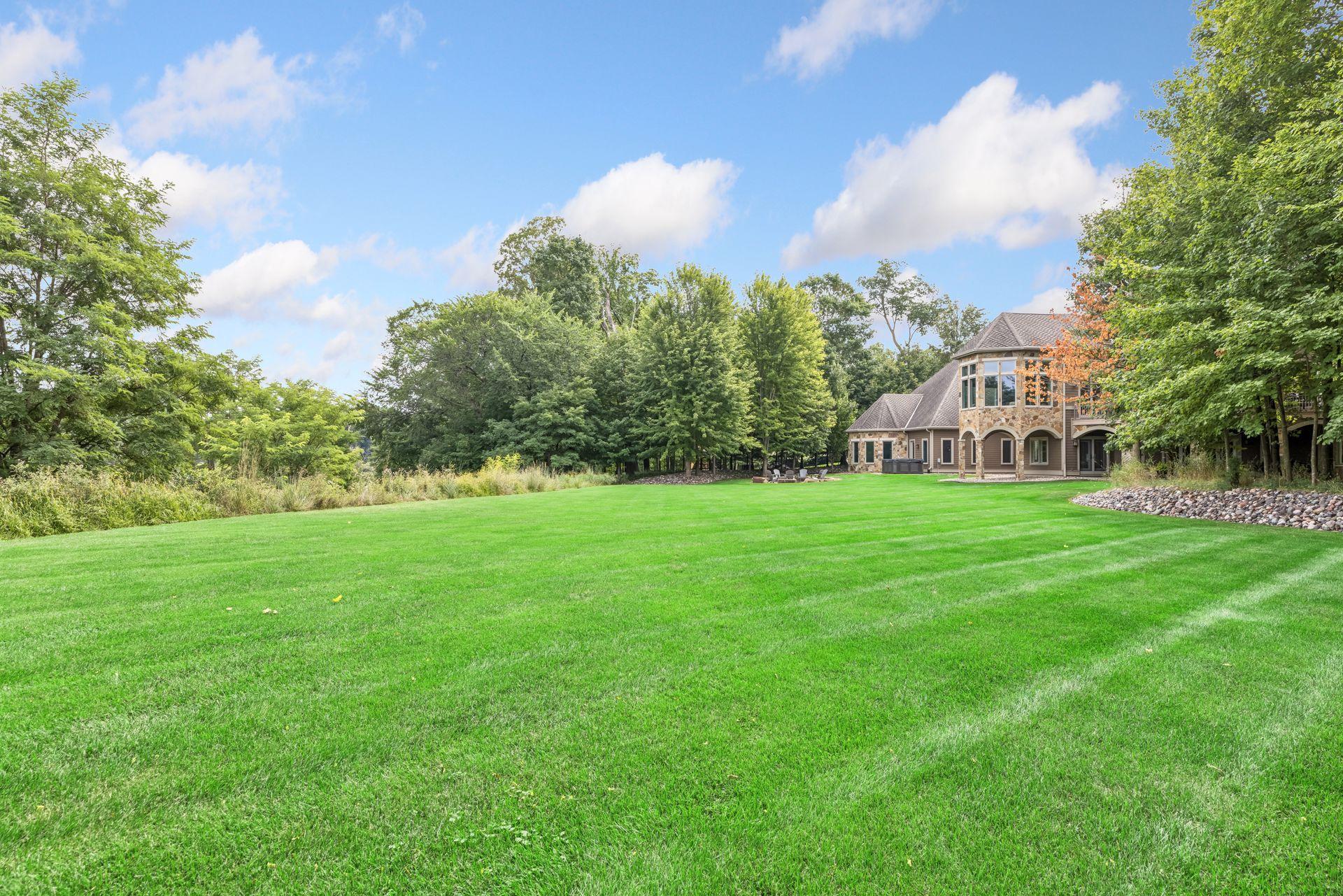 An expansive, flat backyard with lush green space provides an ideal setting for lawn games and gatherings.