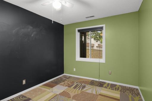 Bedroom three features a chalkboard wall, carpet tiles with views of the back of the home.