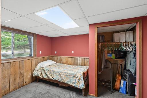 The lower level bedroom combines rustic wood paneling with a comfortable sleeping area and a spacious closet for added storage.