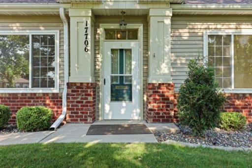 The front door is framed by rich brick pillars and a classic transom window for extra light. A tidy stamped concrete walkway makes for an inviting first impression.