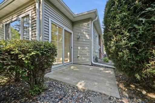 Sliding glass doors open right onto the patio, making indoor to outdoor living effortless. Rounded shrubs and stone edging give the space a polished finish.