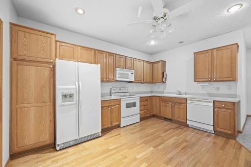 This spacious kitchen offers abundant oak cabinetry with plenty of room for storage and prep. Rich wood floors run throughout, adding warmth to the space.