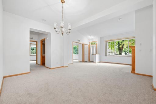 Vaulted ceilings add volume and light to this open dining and living area. Large windows on the far wall bring in a great view of the mature trees outside.