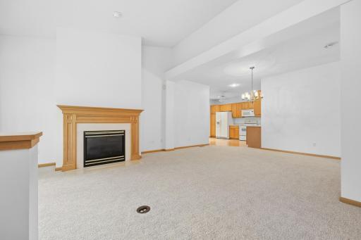 A cozy gas fireplace with a warm wood mantel serves as the focal point of the living room. Soaring ceilings above make this space feel even more open and inviting.