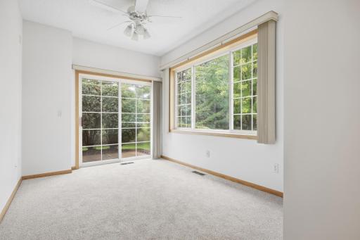 This bright sunroom offers a sliding door out to the patio, surrounded by walls of windows. Wooded views bring plenty of privacy and natural light into the space.