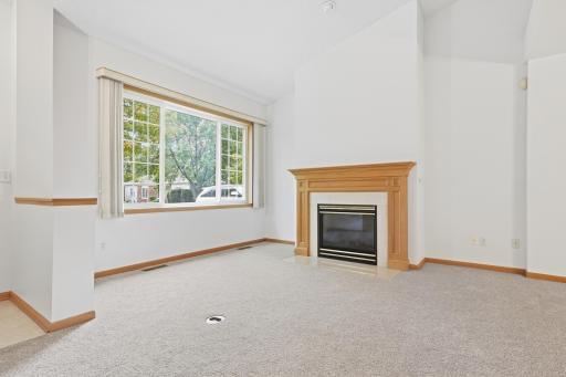 A large picture window fills this vaulted living room with natural light and treetop views. The fireplace sits perfectly centered, framed by tall ceilings on either side.