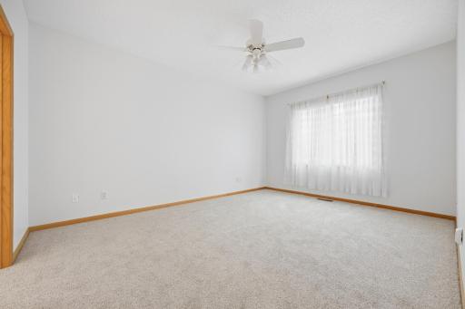 This primary bedroom offers a bright window with a peaceful outdoor view. A ceiling fan and neutral carpet make the space feel comfortable and move in ready.