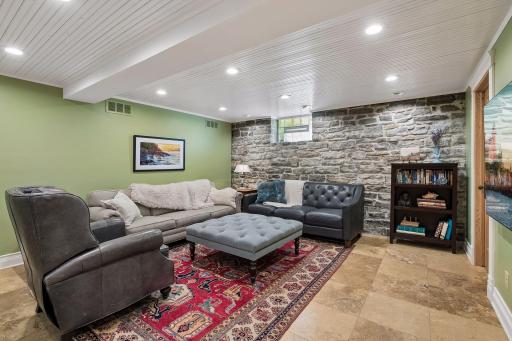The lower level family room features a beautifully preserved stone wall. A charming backdrop to an inviting space.