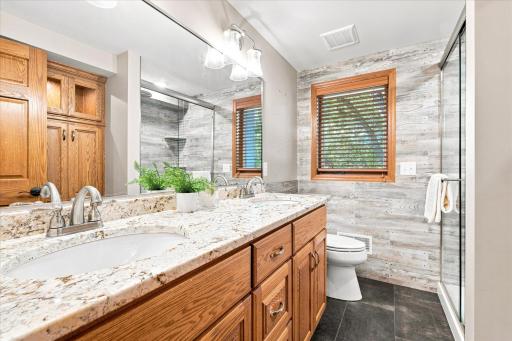 Lower Level 3/4 bath totally renovated in 2021 with new large format floor tile, granite counter top, dual sinks, glass shower doors and barn wood style tile walls.