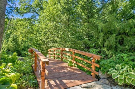 The bridge connects garden pathways to the pond