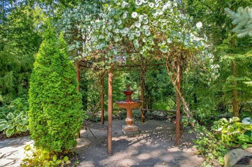 This still gazebo is covered in flowering vines and features a water fountain in the center. There is power for lights too!