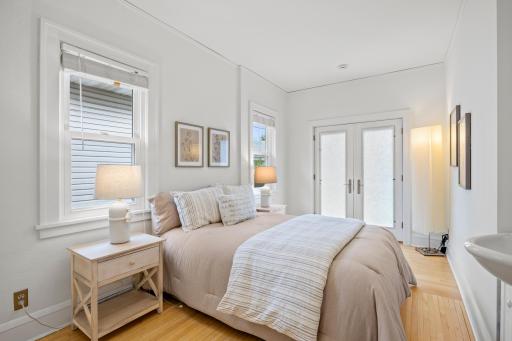 The charming main bedroom features a private sink and flows through elegant French doors to a stunning deck with custom pergolaâyour personal retreat.