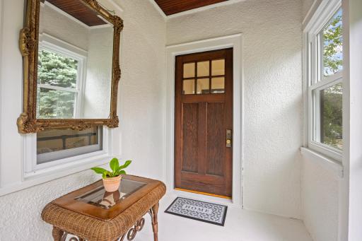 3 season porch with vintage wood door and brass accents flows seamlessly into the home.