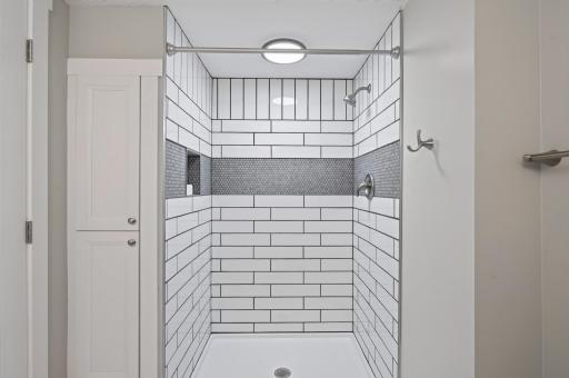 Large ceramic shower lower level bathroom with a linen closet