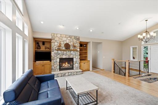 The stunning stone fireplace serves as a beautiful focal point, complemented by custom built-ins and picturesque outdoor views.