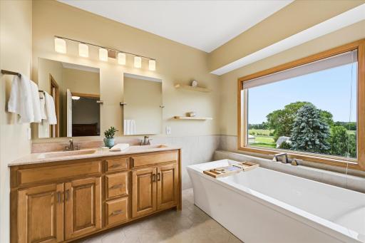 Spacious primary bathroom featuring dual vanities, a soaking tub, and a separate tiled walk-in shower.