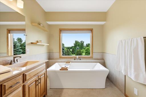 Spacious primary bathroom featuring dual vanities, a soaking tub, and a separate tiled walk-in shower.