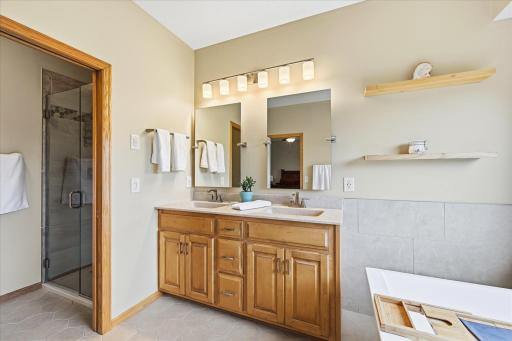 Spacious primary bathroom featuring dual vanities, a soaking tub, and a separate tiled walk-in shower.
